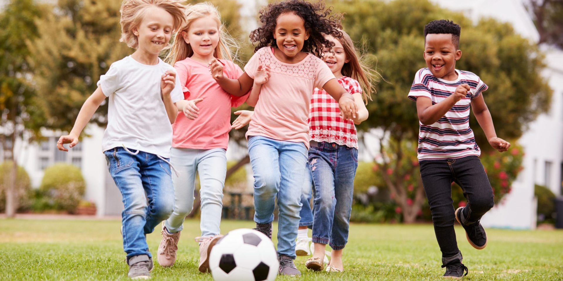 Group Of Children Playing Football With Friends In Park