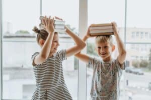 boy and girl holding books on their heads
