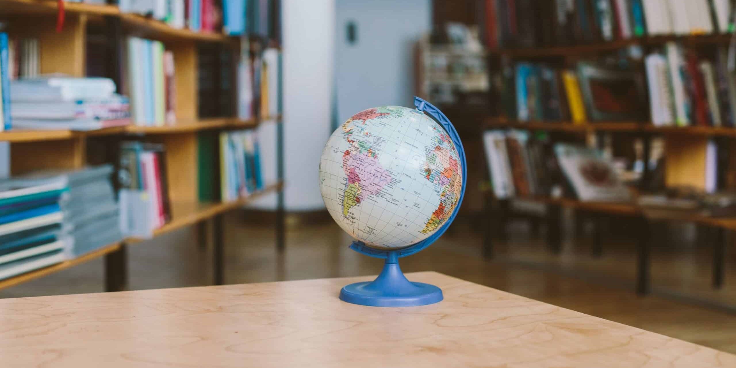 worldschooling A globe surrounded by shelves filled with books