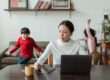 mother working on a laptop at home while her children play